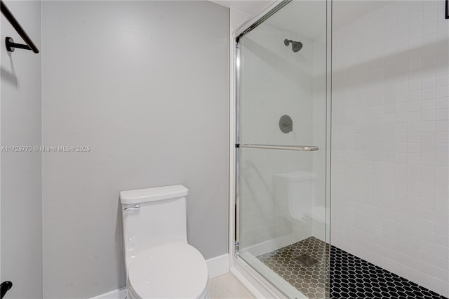 bathroom featuring toilet, a shower with door, and tile patterned flooring