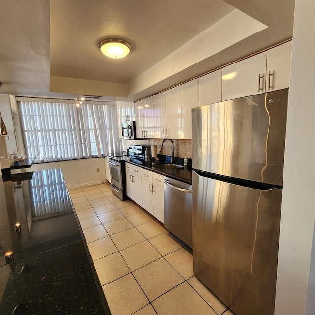 kitchen with white cabinets, stainless steel appliances, sink, and a tray ceiling