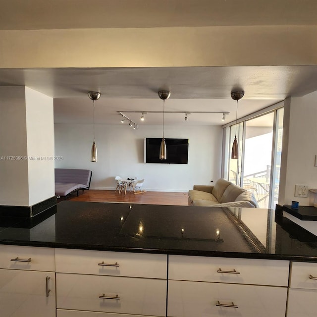 kitchen featuring white cabinetry, dark stone countertops, and hanging light fixtures