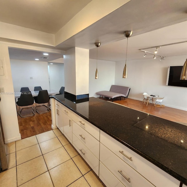 kitchen with white cabinets, dark stone countertops, light tile patterned floors, and pendant lighting