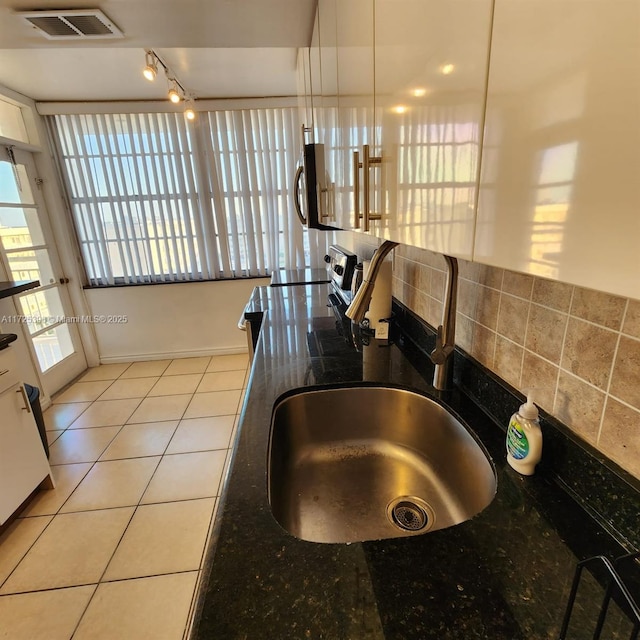 kitchen with sink, light tile patterned floors, dark stone counters, pendant lighting, and appliances with stainless steel finishes