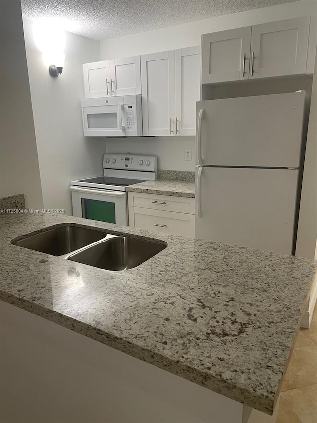 kitchen featuring white cabinets, a textured ceiling, white appliances, kitchen peninsula, and light stone countertops