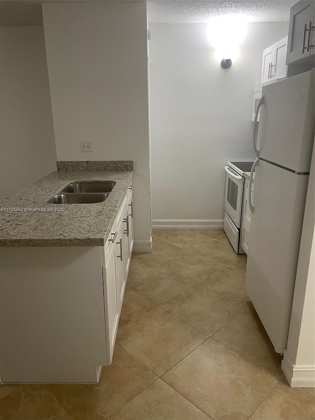 kitchen featuring white appliances, light stone countertops, light tile patterned floors, sink, and white cabinetry