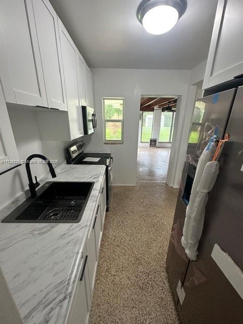 kitchen featuring sink, stainless steel appliances, white cabinetry, and light stone countertops