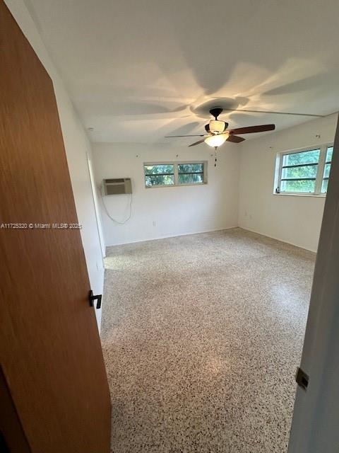 spare room with a wall unit AC and ceiling fan