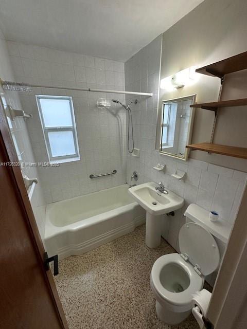 bathroom with tile walls, tiled shower / bath combo, and toilet