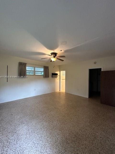 unfurnished room with a wall mounted AC and ceiling fan