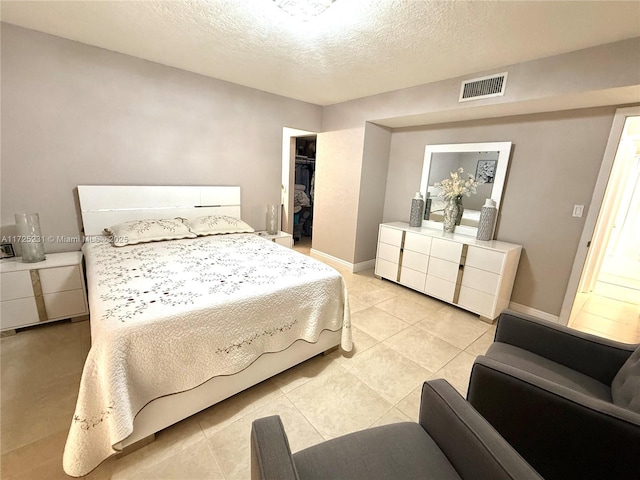 tiled bedroom with a walk in closet, a closet, and a textured ceiling