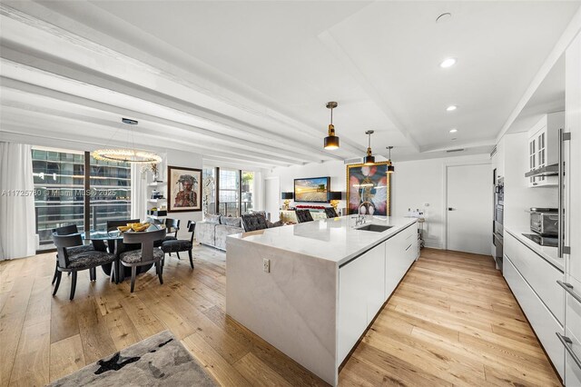 kitchen with decorative light fixtures, kitchen peninsula, sink, and white cabinetry