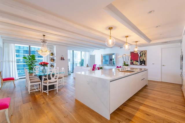 kitchen with decorative light fixtures, white cabinetry, a center island, and light hardwood / wood-style flooring