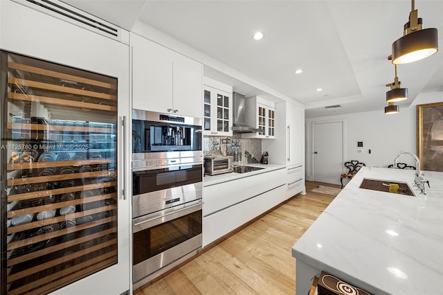 kitchen with decorative light fixtures, backsplash, white cabinets, wall chimney exhaust hood, and beverage cooler