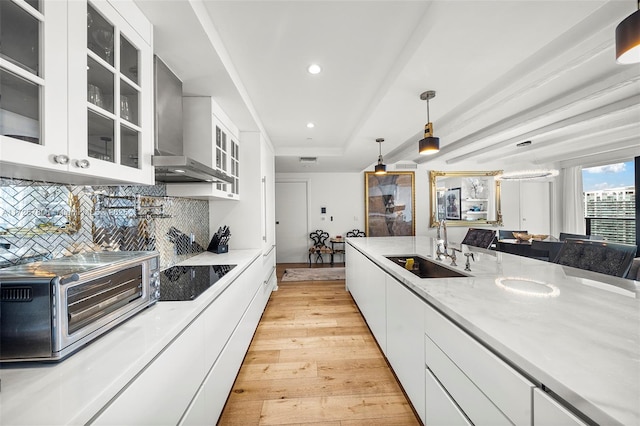 kitchen with pendant lighting, sink, white cabinetry, wall chimney exhaust hood, and black electric cooktop