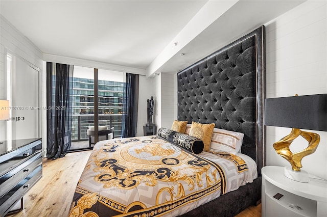 bedroom with a wall of windows, light wood-type flooring, and access to exterior