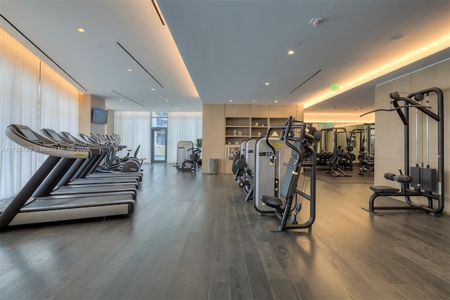 exercise room featuring a wall of windows and dark hardwood / wood-style flooring