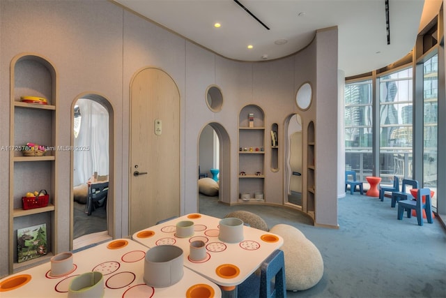 carpeted dining space with a high ceiling and built in shelves