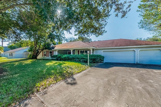 ranch-style home featuring driveway, an attached garage, and a front yard