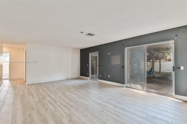 spare room featuring baseboards, a textured ceiling, visible vents, and wood finished floors