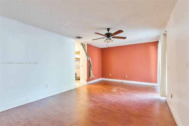 empty room featuring baseboards, visible vents, a ceiling fan, wood finished floors, and a textured ceiling