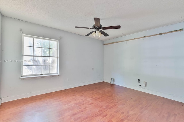 spare room with a textured ceiling, wood finished floors, visible vents, and baseboards