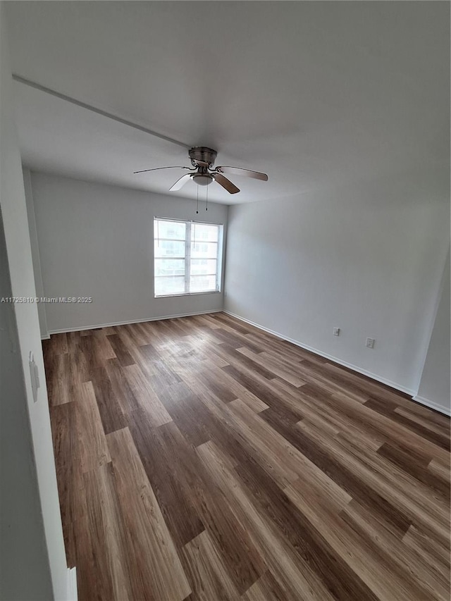 empty room with ceiling fan, baseboards, and dark wood finished floors