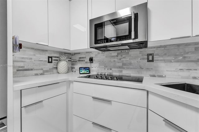 kitchen featuring white cabinets, black electric stovetop, and decorative backsplash