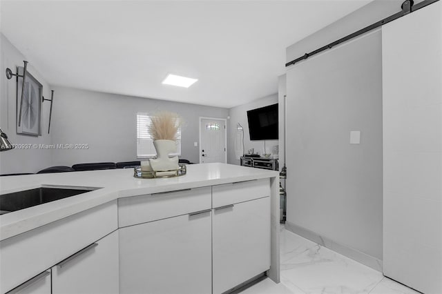 kitchen with white cabinets, a barn door, and sink