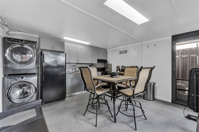 dining area featuring sink and stacked washing maching and dryer