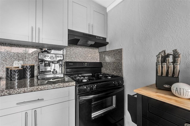 kitchen with black gas range, white cabinets, tasteful backsplash, and dark stone counters