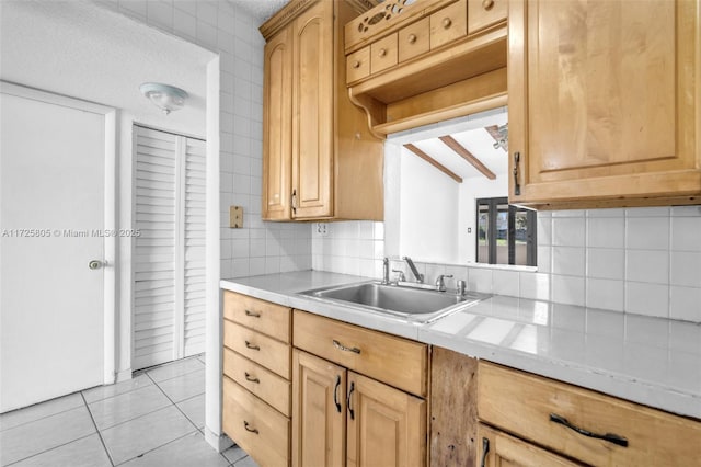 kitchen with light tile patterned flooring, beamed ceiling, sink, decorative backsplash, and light brown cabinets