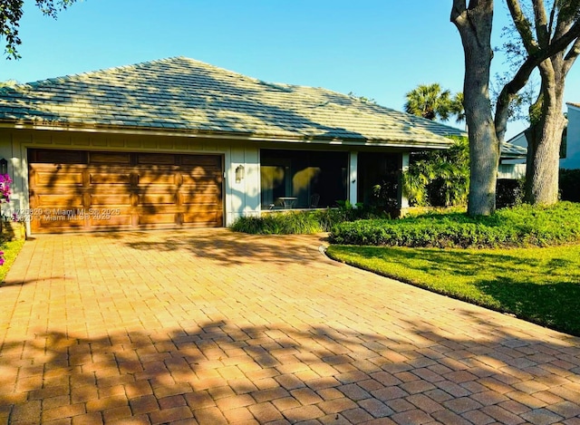 view of front of property featuring board and batten siding, decorative driveway, and an attached garage