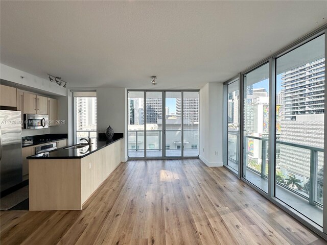 kitchen featuring kitchen peninsula, a textured ceiling, light hardwood / wood-style flooring, appliances with stainless steel finishes, and light brown cabinets