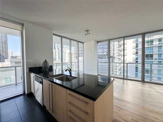 kitchen with expansive windows, a peninsula, dark countertops, stainless steel dishwasher, and a sink