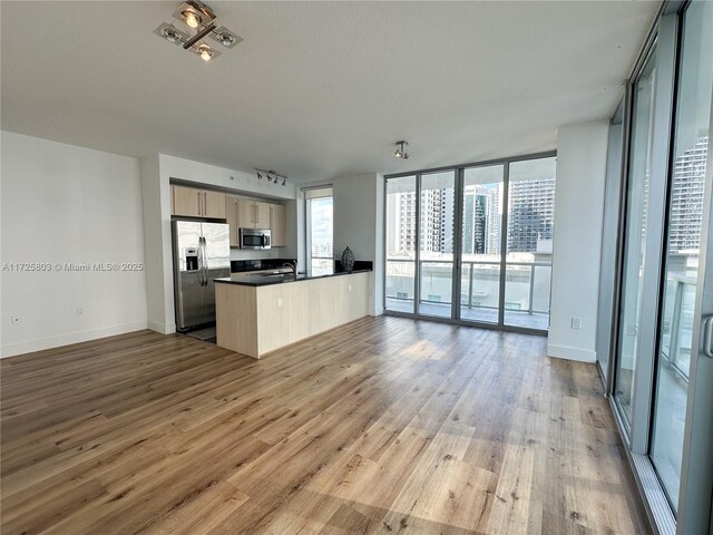 kitchen featuring sink, stainless steel appliances, light brown cabinetry, and a textured ceiling