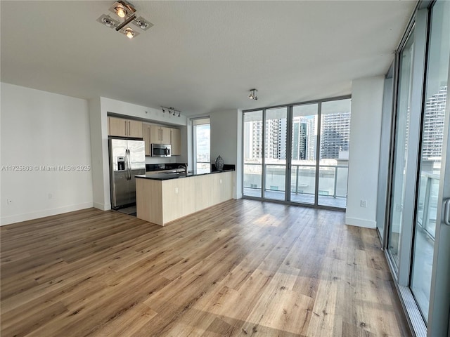 kitchen featuring floor to ceiling windows, open floor plan, dark countertops, appliances with stainless steel finishes, and wood finished floors