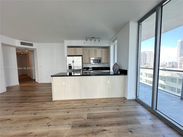 kitchen with a city view, visible vents, appliances with stainless steel finishes, a wall of windows, and dark countertops