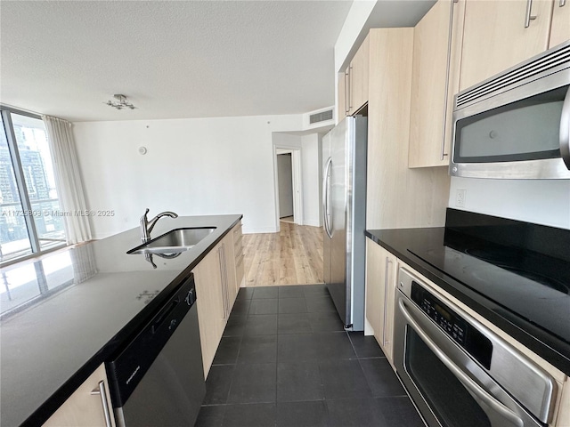 kitchen featuring a sink, visible vents, appliances with stainless steel finishes, and light brown cabinetry