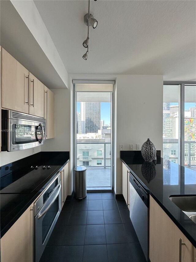 kitchen with a wall of windows, appliances with stainless steel finishes, a view of city, dark countertops, and dark tile patterned floors