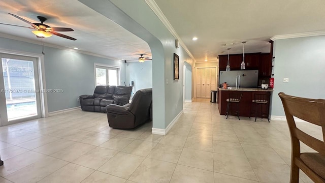 tiled living room with ceiling fan and ornamental molding