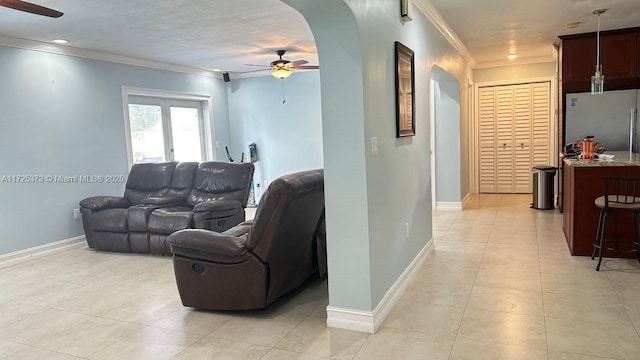 tiled living room with ceiling fan and ornamental molding