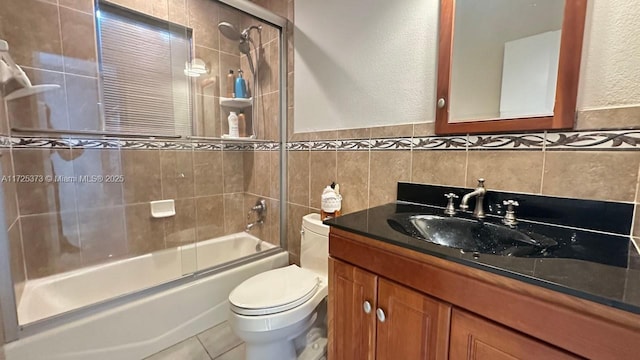 full bathroom with toilet, vanity, tile walls, tile patterned flooring, and shower / bath combination with glass door