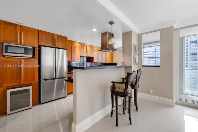 kitchen with wine cooler, appliances with stainless steel finishes, dark countertops, a kitchen breakfast bar, and island range hood