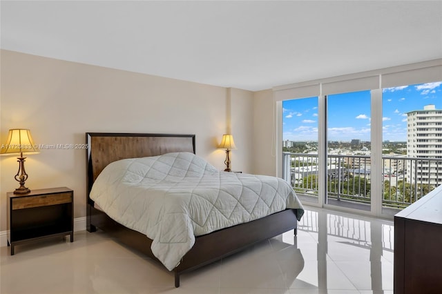 tiled bedroom with expansive windows, a view of city, baseboards, and access to exterior