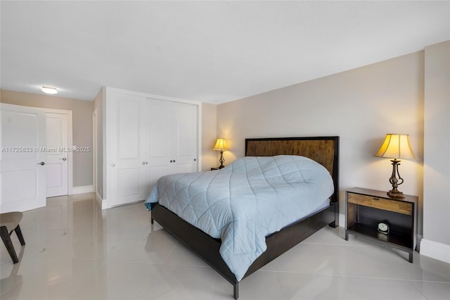 bedroom with a closet, light tile patterned floors, and baseboards