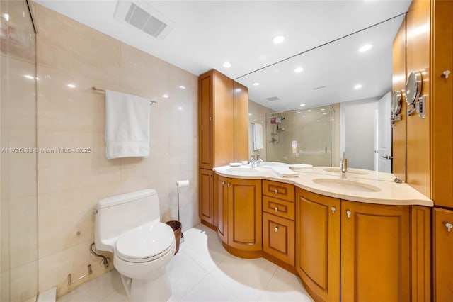 full bath with visible vents, toilet, a stall shower, tile walls, and double vanity