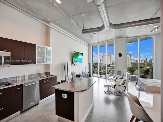 kitchen featuring stainless steel appliances, a center island, expansive windows, sink, and dark brown cabinets