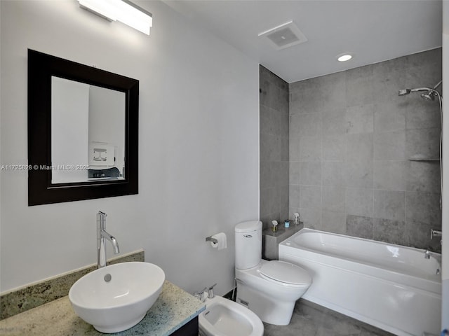 full bathroom featuring toilet, vanity, a bidet, and tiled shower / bath combo