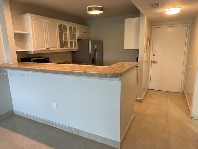 kitchen with stainless steel appliances, white cabinetry, light tile patterned floors, and kitchen peninsula