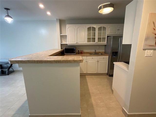 kitchen with kitchen peninsula, appliances with stainless steel finishes, hanging light fixtures, and white cabinetry