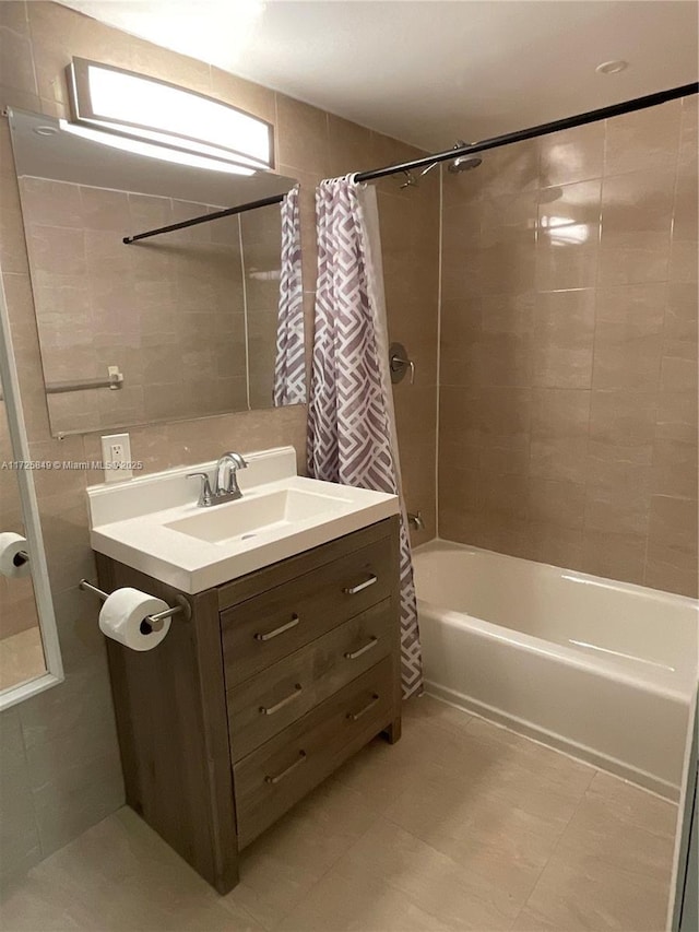 bathroom featuring tile walls, shower / bathtub combination with curtain, and vanity