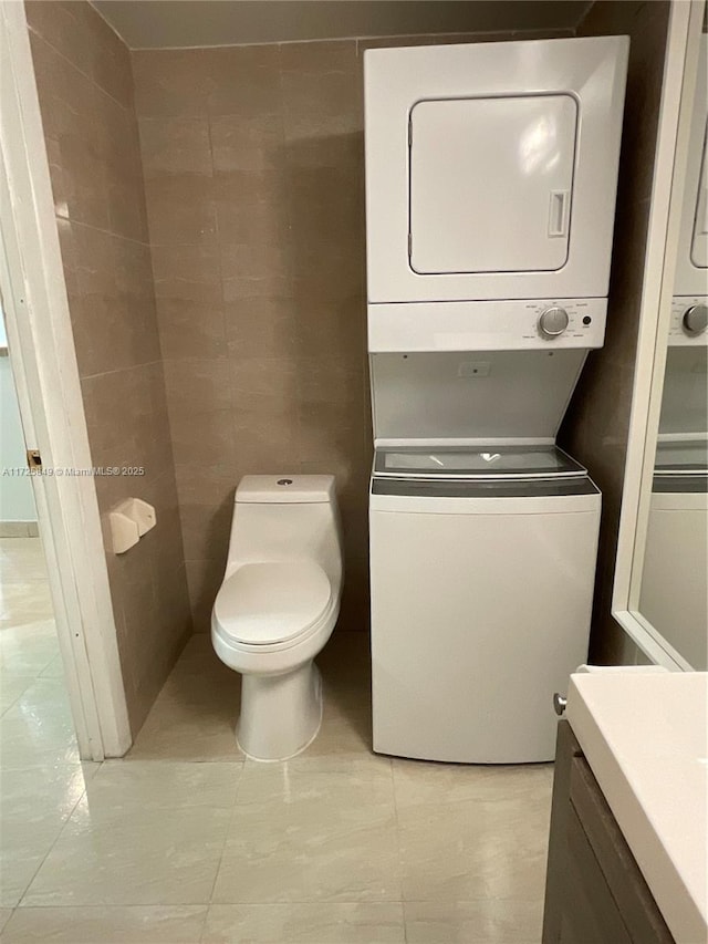 laundry room with stacked washer and dryer and light tile patterned flooring